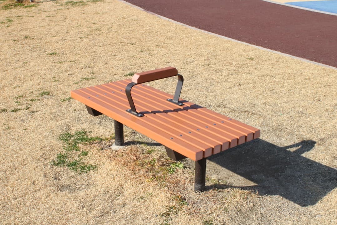 Wooden bench with metal supports on dry grass.