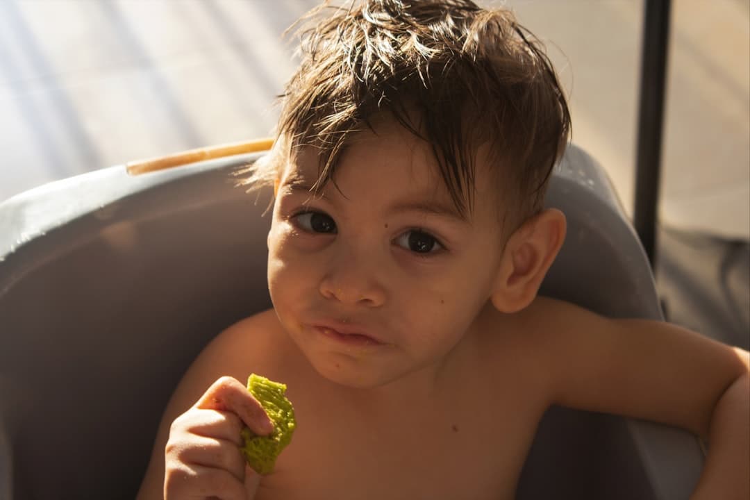 A young child eating a green snack