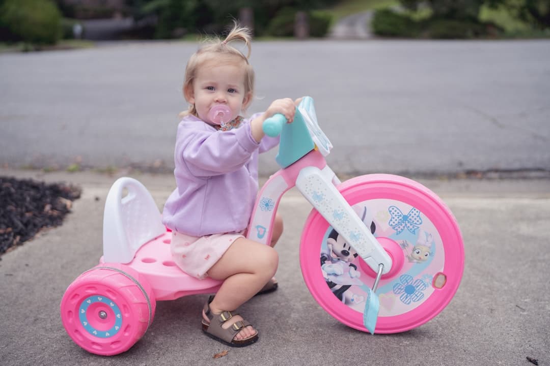 Toddler girl sitting on a pink tricycle outdoors