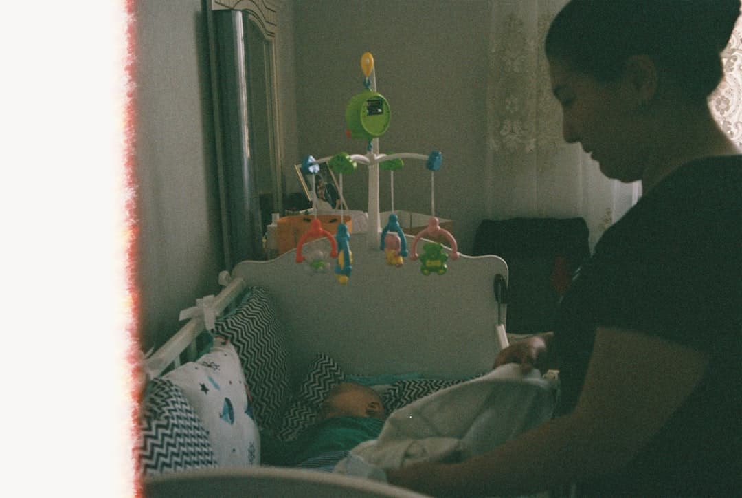 Mother tucking in her baby in a crib