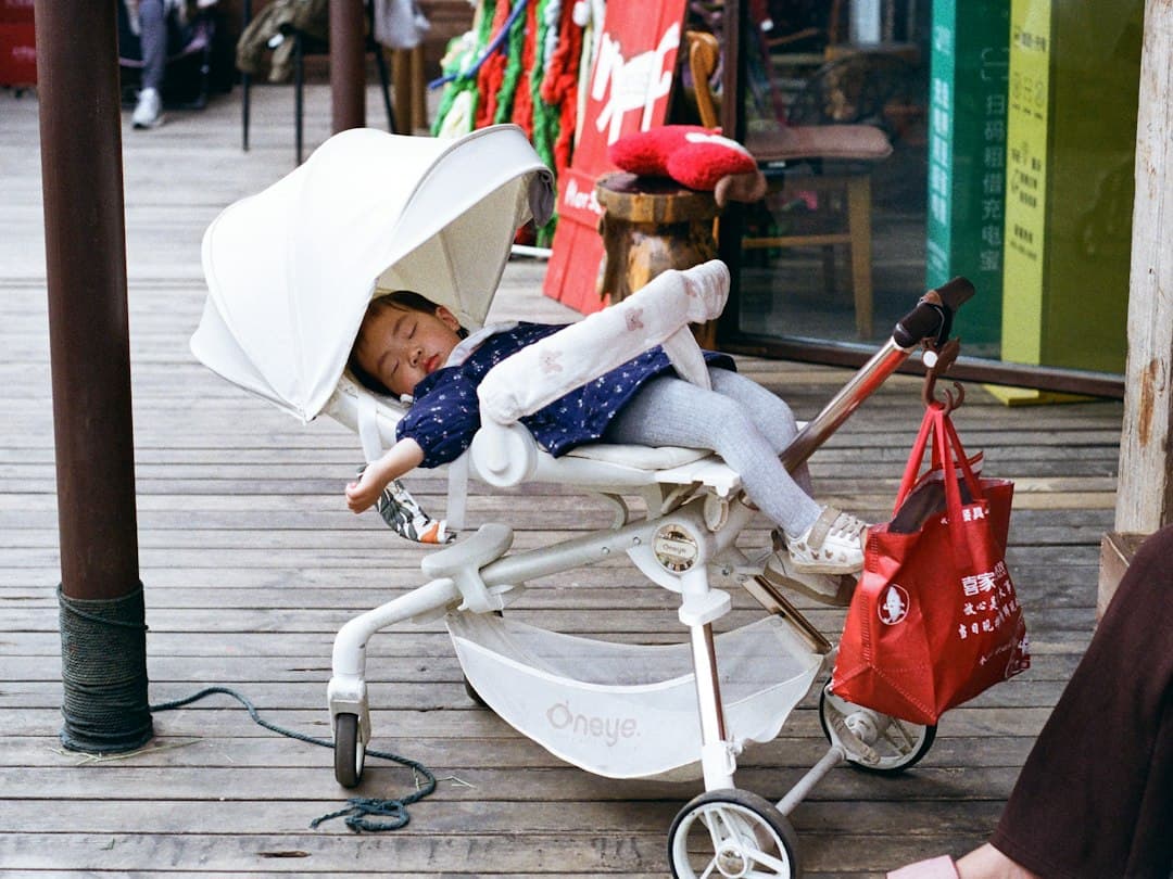 A young child sleeps soundly in a stroller outdoors
