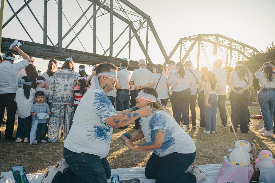People playing a blindfolded game outdoors under a bridge