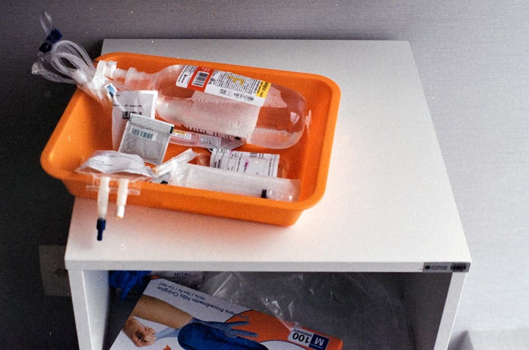 Medical supplies in an orange tray on a white surface.