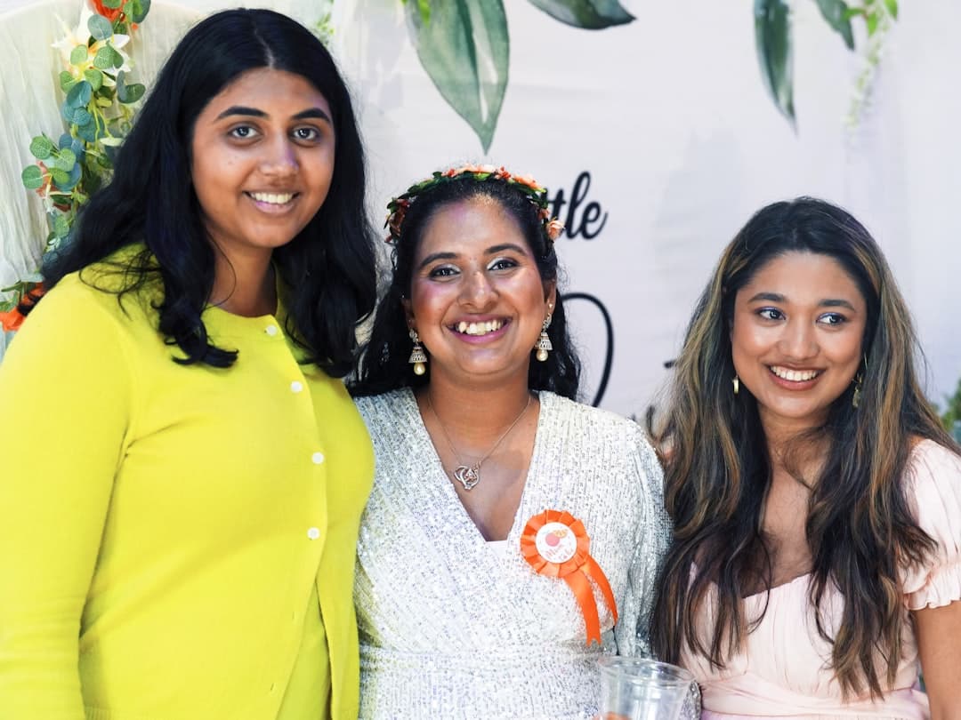 Three smiling women posing together at an event.