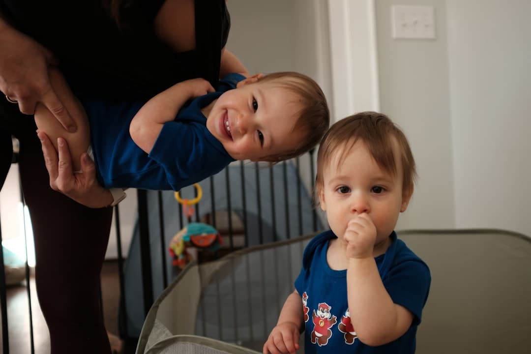 Two babies, one held upside down, smiling.