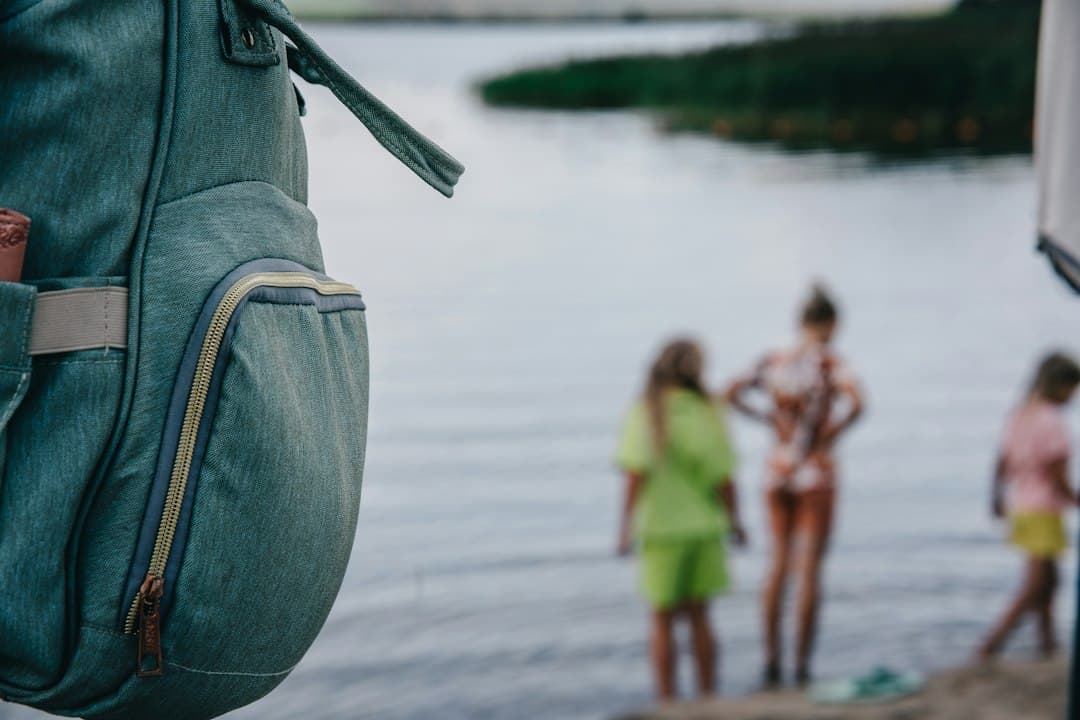 A person is holding a backpack in front of a body of water